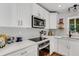 Bright kitchen featuring quartz countertops, modern appliances, stylish backsplash, and white cabinetry at 3026 51St S St, Gulfport, FL 33707
