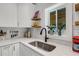 Modern kitchen featuring white cabinets, quartz countertops, stylish backsplash, and stainless steel sink at 3026 51St S St, Gulfport, FL 33707
