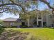 Inviting exterior view of home with lush lawn, mature trees, and outdoor stairwell to the second floor at 3050 Landmark Blvd # 1008, Palm Harbor, FL 34684