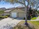 Charming home featuring a two-car garage, mature tree, and exterior staircase to the second level at 3050 Landmark Blvd # 1008, Palm Harbor, FL 34684