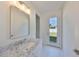 Bathroom featuring a marble countertop, mirror, and an exit door to the backyard at 3913 W Euclid Ave, Tampa, FL 33629