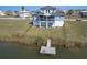 Aerial view of blue home with covered porch, balcony and dock on the canal at 4010 Jewfish Dr, Hernando Beach, FL 34607