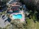 Aerial view featuring a community pool, clubhouse, and parking, set amidst lush trees and greenery at 7807 Hardwick Dr # 115, New Port Richey, FL 34653