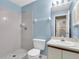 Bathroom with white tile in the shower, a single sink vanity, a toilet, and blue walls at 7807 Hardwick Dr # 115, New Port Richey, FL 34653