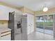 Bright kitchen features a stainless steel refrigerator, tile floors, and sliding glass doors to the lanai at 7807 Hardwick Dr # 115, New Port Richey, FL 34653
