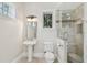 Well-lit half bathroom featuring a pedestal sink, toilet, and a glass-enclosed shower with tiled walls at 808 Idlewood Ave, Tampa, FL 33609