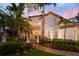 Stately two-story home with manicured lawn, tropical foliage, and exterior lighting at dusk at 808 Idlewood Ave, Tampa, FL 33609