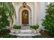 Elegant arched wooden front door with transom window and white pillars, flanked by potted plants on the porch at 808 Idlewood Ave, Tampa, FL 33609