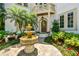 Elegant home entrance featuring a tiered fountain, mature landscaping, a wood door and a small balcony above at 808 Idlewood Ave, Tampa, FL 33609
