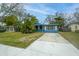 Charming blue home with a long driveway, lush greenery, and palm trees at 8371 55Th N St, Pinellas Park, FL 33781