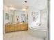 Bright bathroom featuring a soaking tub, double sink vanity, and large mirror at 10211 Quails Landing Ave, Tampa, FL 33647