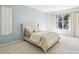 This bedroom features a serene blue accent wall, plush carpeting, and a sunny window framing a beautiful outdoor view at 10211 Quails Landing Ave, Tampa, FL 33647