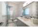 Bright bathroom featuring neutral tile, glass shower door, and gray vanity with marble countertop at 110 Harbor View Ln, Belleair Bluffs, FL 33770