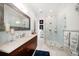 Bright bathroom features a walk-in shower with glass door, a double sink, and marble floors at 110 Harbor View Ln, Belleair Bluffs, FL 33770