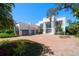 Elegant white home featuring a brick driveway, a three-car garage and lots of curb appeal at 110 Harbor View Ln, Belleair Bluffs, FL 33770