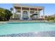 Inviting pool with elegant mosaic tiling leading up to a grand white home with soaring columns at 110 Harbor View Ln, Belleair Bluffs, FL 33770