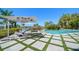 Resort-style backyard with a pool, patio, sun umbrellas, tropical plants, and a waterfront view at 110 Harbor View Ln, Belleair Bluffs, FL 33770