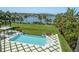 Backyard view with inground pool, lawn, and landscaping overlooking the water and bridge at 110 Harbor View Ln, Belleair Bluffs, FL 33770