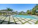Luxury outdoor pool area with lounge chairs, manicured lawn, and serene waterfront views with mature palm trees at 110 Harbor View Ln, Belleair Bluffs, FL 33770