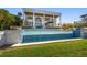Luxurious pool featuring detailed tile work, paired with a large, modern home with stately white columns at 110 Harbor View Ln, Belleair Bluffs, FL 33770