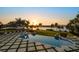 A serene backyard with a pool featuring a sunset view over the water, surrounded by palm trees at 110 Harbor View Ln, Belleair Bluffs, FL 33770