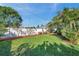 A large backyard features a lush lawn, a white privacy fence, and shade trees for outdoor enjoyment at 2021 58Th S St, Gulfport, FL 33707
