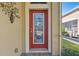 Close up view of the home's detailed glass front door with a vibrant red frame and manicured landscaping at 2253 Oakley Green Dr # 26, Sun City Center, FL 33573