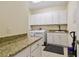 A laundry room featuring granite countertops, white cabinets, a sink, and tile floors at 2253 Oakley Green Dr # 26, Sun City Center, FL 33573