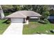Aerial view of home featuring a garage, driveway, manicured lawn, and mature landscaping at 2457 Orangepointe Ave, Palm Harbor, FL 34683