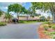 Main entrance to the Auditorium and Clubhouse at Highland Lakes showcases lush landscaping and mature trees at 2873 Doone Cir, Palm Harbor, FL 34684