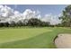 Scenic view of the golf course featuring lush green grass and mature trees under a partly cloudy sky at 2873 Doone Cir, Palm Harbor, FL 34684