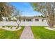 Charming single-story home with a well-manicured lawn, a white picket fence, and a brick walkway at 292 42Nd Ave, St Pete Beach, FL 33706