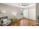 Bright bedroom featuring a ceiling fan, wood floors, gray chair, and double door closet at 5141 Sunnydale W Cir, Sarasota, FL 34233