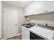 Well-lit laundry room with white washer and dryer, cabinets, and a door at 5141 Sunnydale W Cir, Sarasota, FL 34233