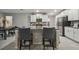 Well-lit kitchen with an island, gray barstools, stainless steel appliances, and a view into the dining area at 6241 Spider Lily Way, New Port Richey, FL 34653