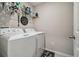 Bright laundry room featuring washer, dryer, wire shelf, and dark themed decorations at 6241 Spider Lily Way, New Port Richey, FL 34653