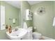 Charming half-bathroom with a decorative flower, cabinet, white sink, and soft green walls at 6345 Vista Verde E Dr, Gulfport, FL 33707