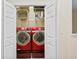 Open view of the laundry room with a red washer and dryer, wire racks, and white folding doors at 6345 Vista Verde E Dr, Gulfport, FL 33707