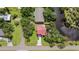 An aerial view of a red-roofed home nestled in a lush, tree-filled landscape, close to a tranquil waterfront area at 9501 Alice Ln, Riverview, FL 33578