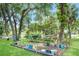 Landscaped backyard with garden bed, lush green grass, and serene pond views beyond at 9501 Alice Ln, Riverview, FL 33578
