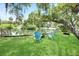 Lush backyard features vibrant green grass, pond views, and inviting blue Adirondack chairs at 9501 Alice Ln, Riverview, FL 33578