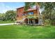 Back exterior view of a two-story home with a wooden deck and a lush lawn at 9501 Alice Ln, Riverview, FL 33578