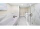 Sleek bathroom featuring a soaking tub, glass-enclosed shower, and modern fixtures with neutral tile at 1100 Pinellas Bayway S # H2, Tierra Verde, FL 33715