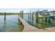 Wooden pier with boat lifts extending over calm, shimmering water at 1100 Pinellas Bayway S # H2, Tierra Verde, FL 33715
