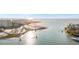 Scenic aerial view of a waterfront property with a sandy beach, calm ocean waters, and distant city skyline at 1100 Pinellas Bayway S # H2, Tierra Verde, FL 33715
