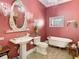 Elegant pink bathroom with an oval mirror, chandelier, pedestal sink, and clawfoot tub at 12010 Hardaman Pl, Tampa, FL 33618