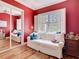 Cozy red bedroom featuring hardwood floors, a bright window, and a comfortable white couch at 12010 Hardaman Pl, Tampa, FL 33618