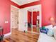 Comfortable red bedroom with hardwood floors and a mirrored closet and a white couch at 12010 Hardaman Pl, Tampa, FL 33618