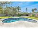 Private backyard showcasing a freeform pool surrounded by a spacious travertine patio and lush landscaping at 1842 Oklahoma Ne Ave, St Petersburg, FL 33703