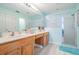 Bright bathroom featuring a double sink vanity, a large mirror, and a shower with glass door at 29312 Marker Loop, San Antonio, FL 33576